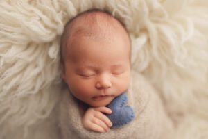 Newborn baby boy holding a blue heart in a Baltimore MD photography studio