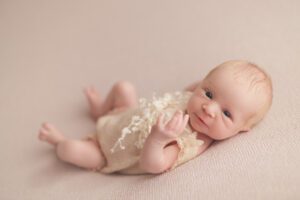 Awake newborn baby in a peach colored outfit at Gettysburg photography studio