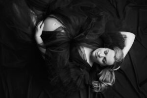 Stunning pregnant woman wearing a gown posed laying on the floor in a Gettysburg maternity studio