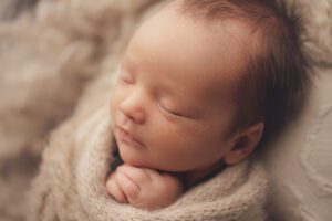 Sleeping newborn baby wrapped in neutral tones during a Baltimore newborn photography studio session